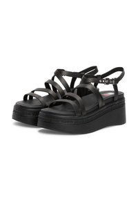 Sandales à plateforme noires avec plusieurs lanières plates et une bride ajustable à la cheville. Présente une semelle texturée avec la marque "TOMMY JEANS".