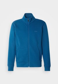 Blå zip-up sweatshirt med hög krage, två framfickor, ribbade mudd och en diskret logotyp på bröstet. Mjuk tygstruktur.