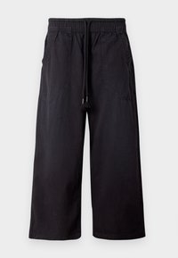 Zwarte wijde broek van katoen, voorzien van een elastische tailleband met trekkoord, twee zijzakken en een gladde, matte textuur.