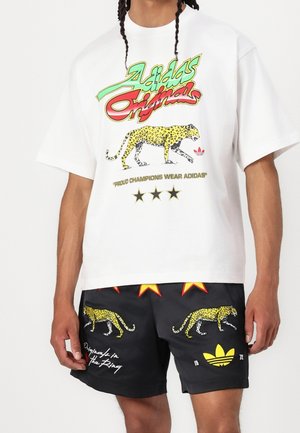 Biała koszulka z krótkim rękawem z kolorowym napisem "Adidas Originals" oraz grafiką żółtej pantery. Czarne szorty z nadrukiem pantery i żółtymi akcentami.