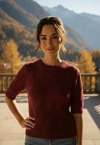 Sweter dzianinowy w kolorze burgundowym z fakturowanym, falistym wzorem, krótkimi rękawami i okrągłym dekoltem, zestawiony z dżinsami.