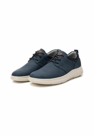 Zapatillas de deporte azul marino con un upper texturizado, suela beige contrasta, perforaciones mínimas y acentos marrones en los cordones y la lengüeta.
