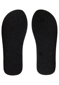 Semelles de chaussures en caoutchouc noir avec une surface texturée présentant des motifs géométriques et deux indentations circulaires près du centre.