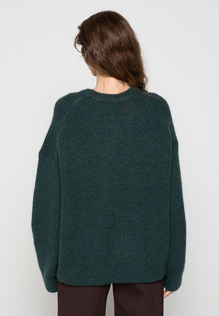 Dunkelgrüner Strickpullover mit lockerer Passform, Raglanärmeln und geripptem Kragen und Saum. Weicher Stoff, minimalistisches Design.