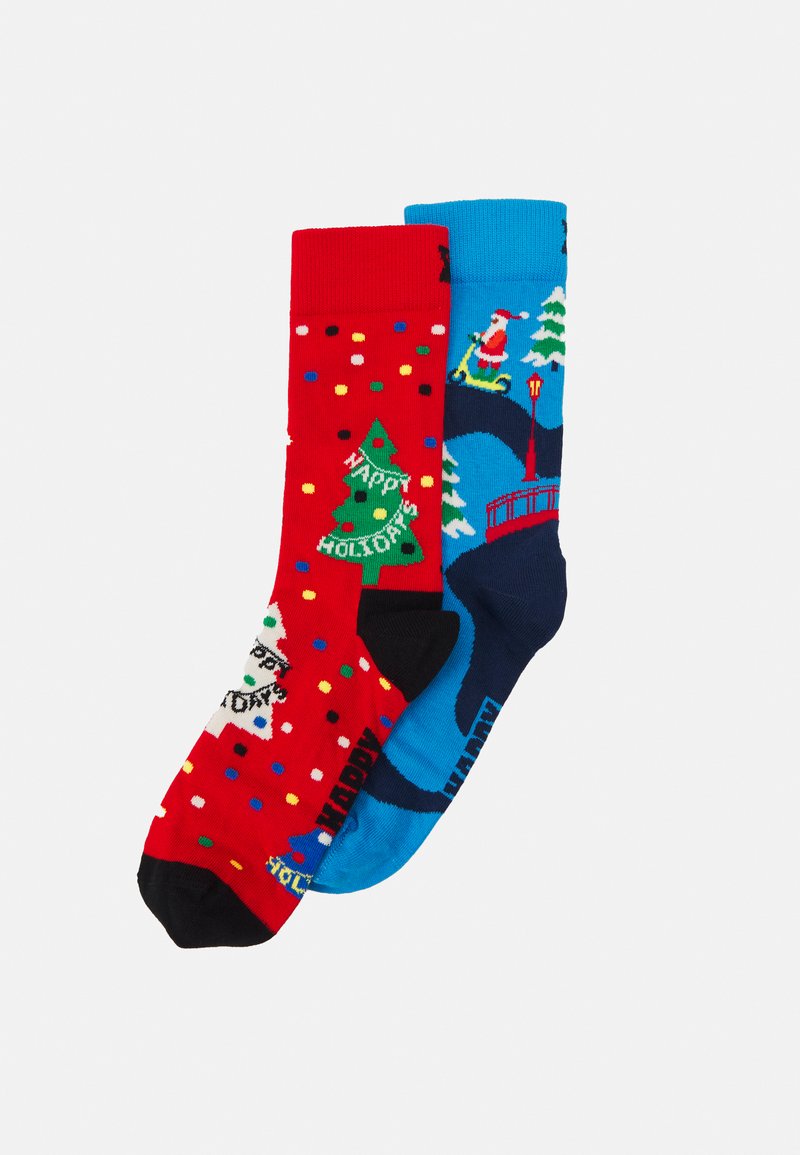 Red and blue holiday-themed socks with festive patterns; red with trees and dots, blue featuring Santa and a bridge. Cotton blend fabric.