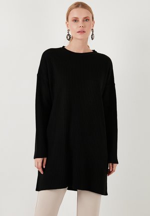 Black ribbed pullover dress with a relaxed fit, long sleeves, and a round neckline, featuring side slits for ease of movement.