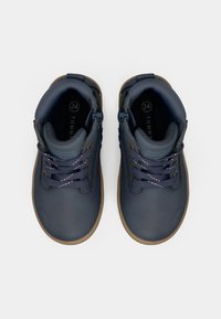 Zapatos de cuero azul hasta el tobillo con una superficie texturizada, puntera redondeada y suela de goma marrón. Presentan acentos en azul claro y cordones con patrón.