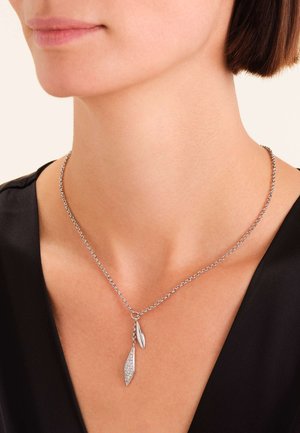 Srebrna ogrlica sa lancem i dva privjeska u obliku lista, jedan glatki, a drugi ukrašen malim prozirnim kamenčićima.