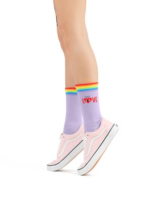 Pink canvas sneakers with black sole, paired with lavender crew socks featuring rainbow stripes and red “LOVE” graphic design.