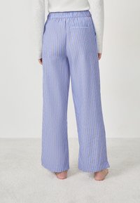 Pantalons à larges jambes rayés bleu et blanc avec une taille élastique, dotés d'une poche arrière et d'une texture douce et lisse.