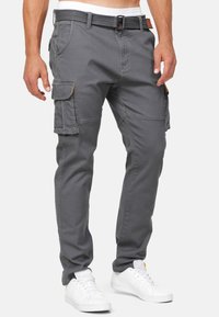 Pantaloni cargo grigi realizzati in tessuto resistente, con numerose tasche, una cintura con fibbia e un design a gamba affusolata.