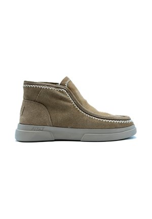 Botas de tobillo de ante marrón con una suela de goma gris moldeada, que presenta costuras blancas en contraste a lo largo de los bordes. Diseño sin atar, tipo slip-on.