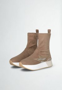 Stivali alla caviglia in suede marrone con una finitura liscia, suola spessa bianca e dettaglio a stella glitterata sul lato; dotati di linguette per una facile calzata.