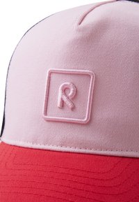 Różowo-czerwona czapka z teksturowanym, usztywnionym daszkiem, haftowanym logo w kwadracie oraz kontrastującymi detalami stębnowania.