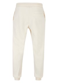 Joggers color crema con cintura elástica, bolsillos laterales y puños acanalados. Textura suave con un solo bolsillo trasero.