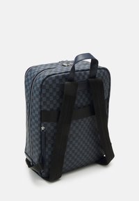 Mochila xadrez azul com exterior texturizado, duas alças pretas e fecho com zíper, apresentando acessórios metálicos e cantos reforçados.