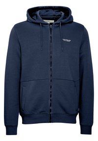 Marineblå zip-up hettegenser med myk tekstur, med snøring på hetten, sidelommer og et lite hvitt logo-detalj på brystet.