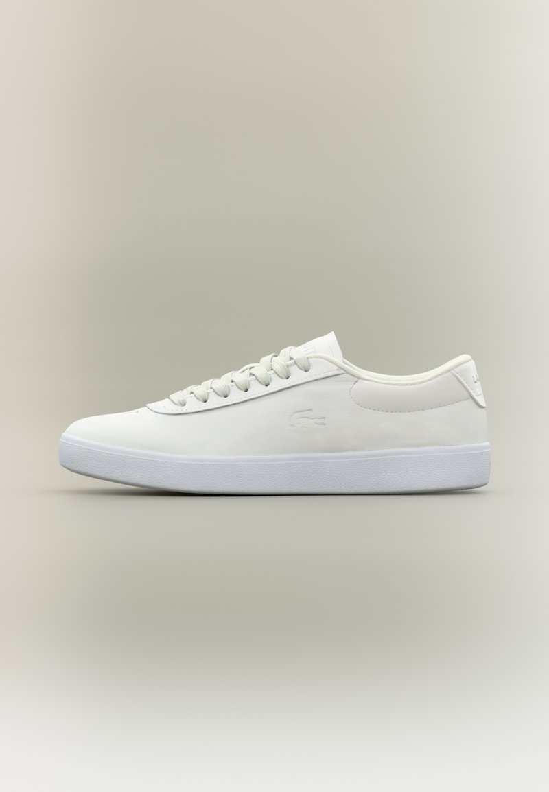 Niskie, białe skórzane trampki z białymi sznurowadłami i teksturowaną, białą podeszwą, wyeksponowane w profilu na tle neutralnej, gładkiej powierzchni.