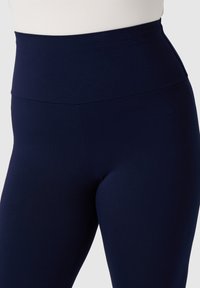 Leggings a vita alta color blu navy realizzati in tessuto elasticizzato, caratterizzati da una texture liscia e un design senza cuciture, adatti a diverse attività e per il comfort.