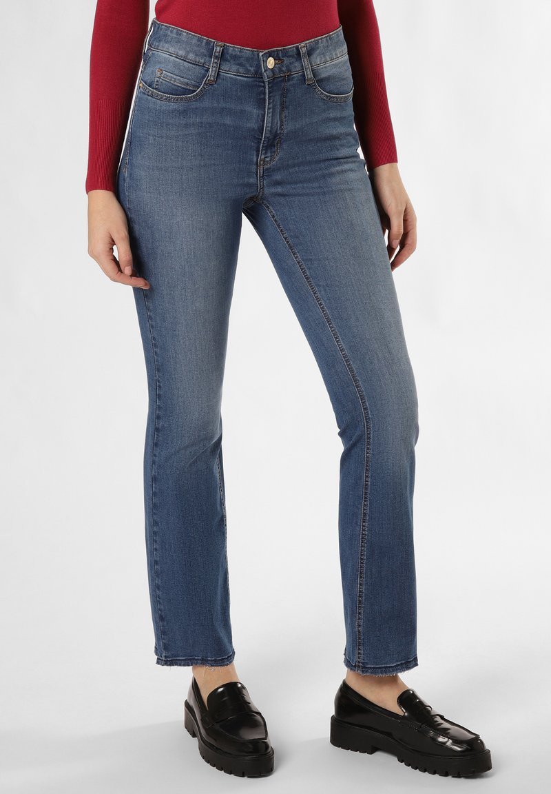 Blauwe denim jeans met een hoge taille, taps toelopende broekspijpen en een licht rafelrandje; gecombineerd met zwarte platform loafers. Met voorzakken.