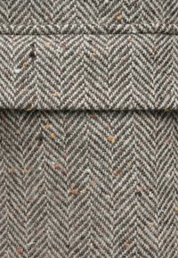 Tkanina so vzorom rybej kosti v sivej farbe s farebnými bodkami, vyrobená z mäkkej, textúrovanej zmesi vlny.