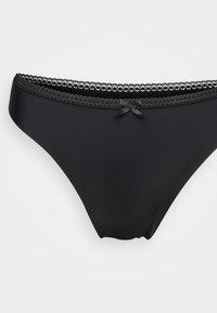 Zwarte bikini slipjes voor vrouwen met kantafwerking en een klein strikje in het midden van de tailleband op een witte achtergrond.