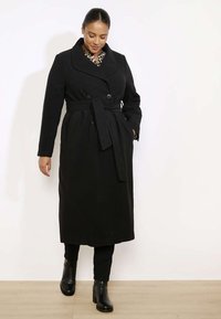 Czarny długi płaszcz z podwójnym zapięciem, z paskiem w talii, szerokim kołnierzem i teksturowanym materiałem. Posiada długie rękawy i prosty krój.