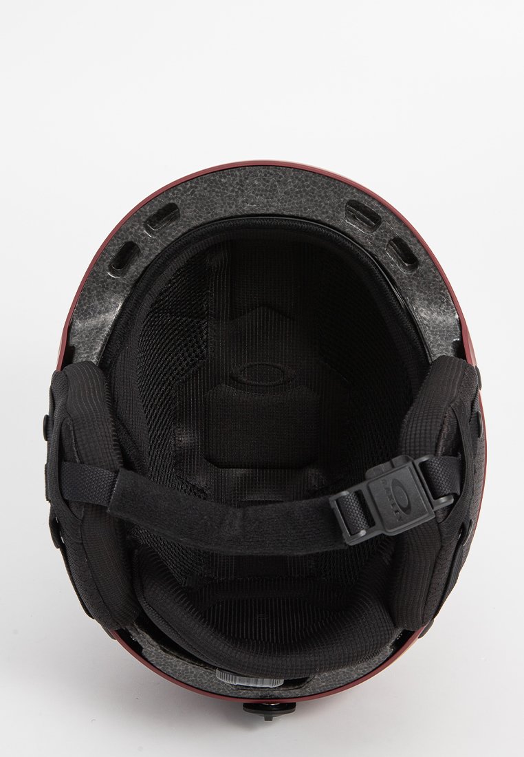 Innenansicht eines roten Skihelms mit gepolstertem schwarzen Futter, verstellbarem Kinnriemen, Belüftungsöffnungen und strukturiertem grauem Außenschale. Kompakte, runde Form.