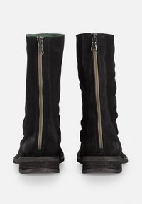 Black suede ankle boots with a slouchy design, featuring a silver zipper along the side, and a slight worn texture on the sole.