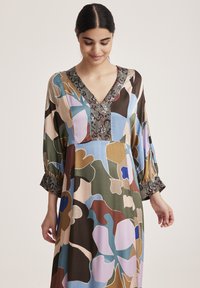 Langes, fließendes Kleid mit mehrfarbigen abstrakten Blumenmustern. Es hat einen V-Ausschnitt und weite Ärmel mit einem dekorativen Bündchen an den Manschetten.
