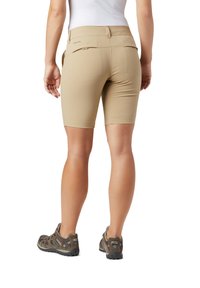 Pantaloni corti beige elasticizzati realizzati in materiale leggero con vita media, dotati di tasche posteriori e una superficie liscia, indossati con scarpe marroni.