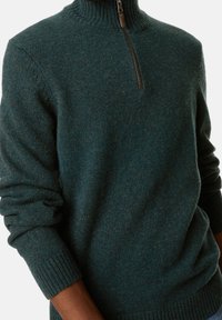 Donker teal sweater met een hoge kraag en een halve ritssluiting, met ribgebreide manchetten en zoom. Zacht van textuur, gebreide stof en een lichte gemêleerde patroon.