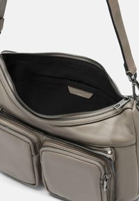 Borsa in pelle grigia con numerose tasche con zip. L'interno presenta una fodera in tessuto nero e un'etichetta del produttore. Texture liscia, design moderno.