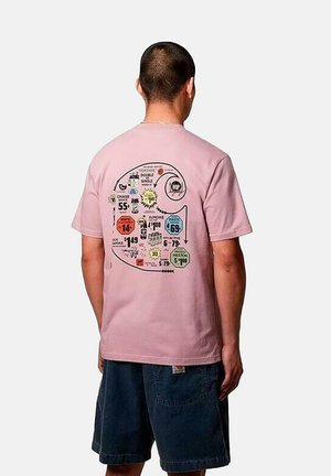 T-shirt en coton rose avec un graphique de vague au dos, présentant diverses imprimés colorés et éléments textuels dans différentes polices.
