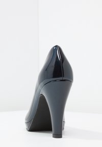 Scarpa con tacco alto in vernice nera, con punta affusolata e tacco a stiletto sottile, caratterizzata da una superficie liscia e lucida e un retro arrotondato.