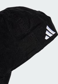 Gorro de pana negra con una superficie texturizada, logo lateral en blanco y un ajuste ceñido. El diseño es simple y funcional.