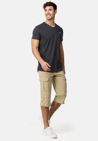 Grå V-hals t-shirt i blødt stof, parret med beige cargo shorts med flere lommer og opsmøgte manchetter, suppleret med hvide sneakers.