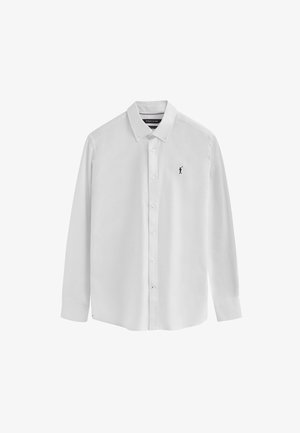 Chemise blanche à manches longues et à boutons, en coton lisse. Présente un col pointu, des boutons beiges et un petit logo marine sur la poitrine.