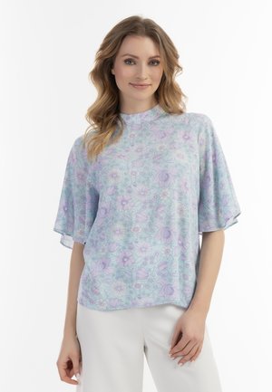 Lyst, kortærmet top i pastelfarvet blå med et blomstermønster i lilla nuancer; løs pasform og rund udskæring.