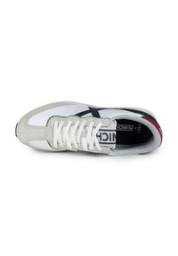 Zapatilla blanca y gris con materiales de ante y textil, que presenta un cierre con cordones, acentos en negro y una etiqueta en la lengüeta.