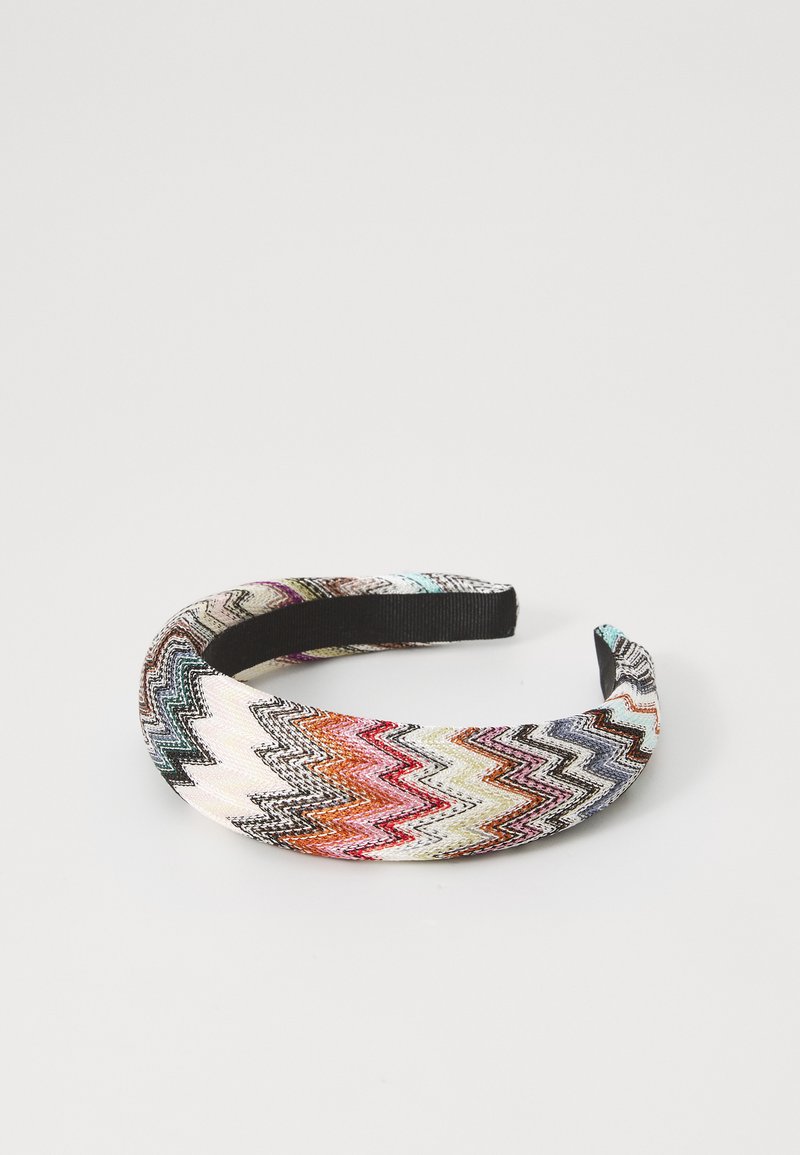 Fascia per capelli con motivo zigzag multicolore e foderata internamente in nero, esposta su uno sfondo leggero e semplice.