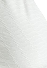 Tecido branco com um padrão de textura ondulada, apresentando detalhes de costura finos. Material macio com uma aparência suave e um brilho sutil.