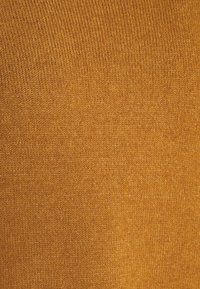 Stickad tyg i en varm senapsgul färg, med en slät textur och fin ribbning, utan synliga mönster eller utsmyckningar.