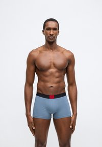 Ανδρικά μπόξερ Hugo σε ανοιχτό μπλε χρώμα, με μαύρη ελαστική μέση που φέρει κόκκινο λογότυπο. Ομαλό ύφασμα, εφαρμοστό σχέδιο.