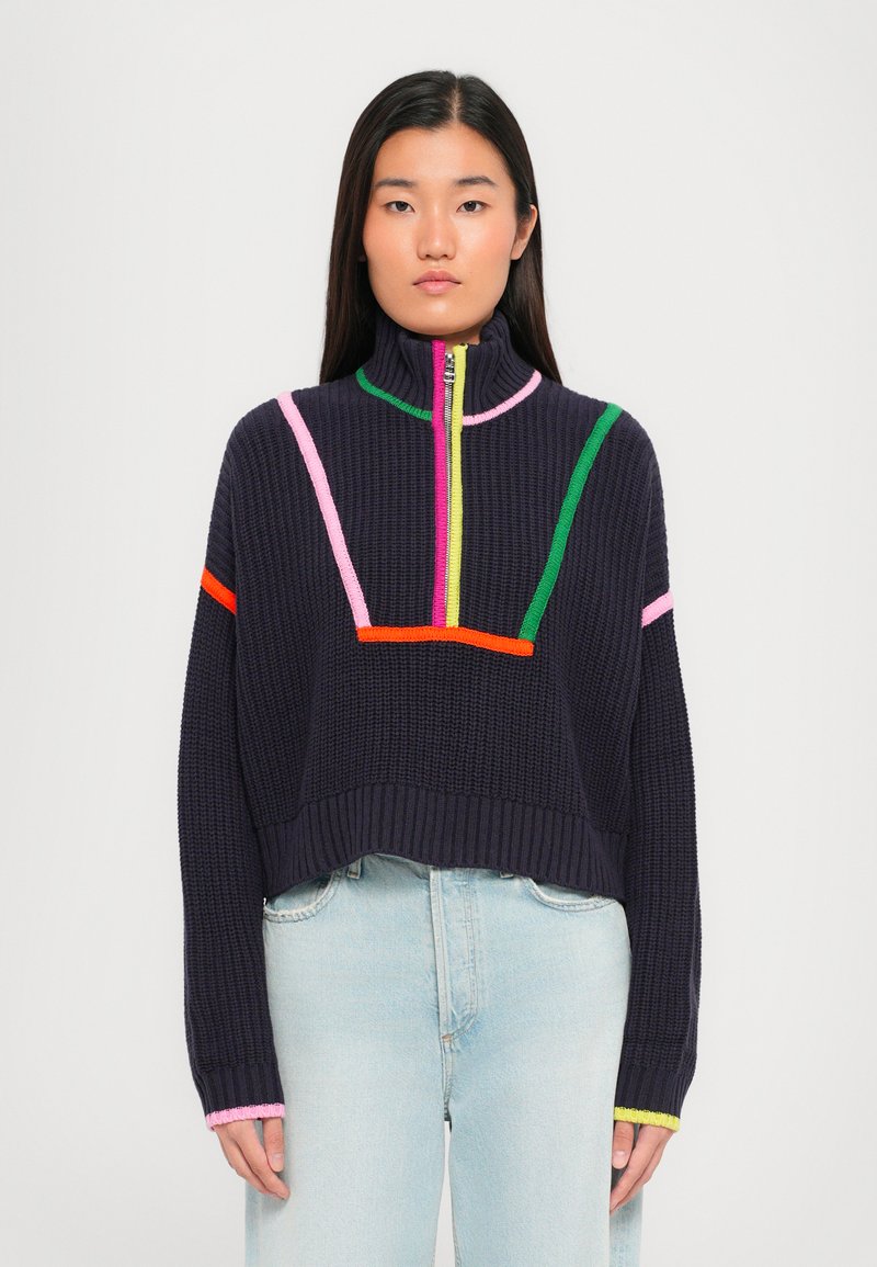 Marineblauw cropped sweater met een hoge kraag, kenmerkt zich door contrasterende kleurvlakken in roze, groen en oranje. Ribbeltextuur en lange mouwen.