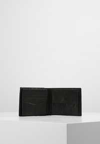 Sort læderpunge åbnet, med flere kortlommer og en større lomme. Glat tekstur med et klassisk design.
