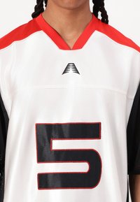 Camisa deportiva blanca con acentos rojos, mangas de malla negra, cuello en V y el número "5" destacado en negro con contorno rojo.