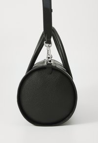 Round black leather bag with a textured finish, featuring a top handle and a detachable strap, silver hardware, and a seamless design.