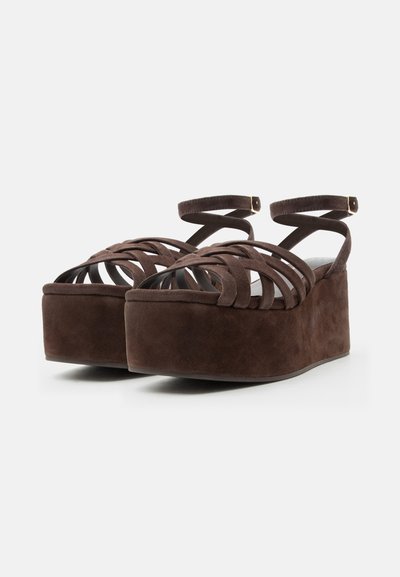 Rjave semiš platformske sandale z več trakovi spredaj in zaponkami okoli gležnja, prikazane na belem ozadju.