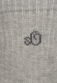 Tessuto grigio a maglia con un discreto design del logo nero. La trama è a coste, con un aspetto morbido e caldo.